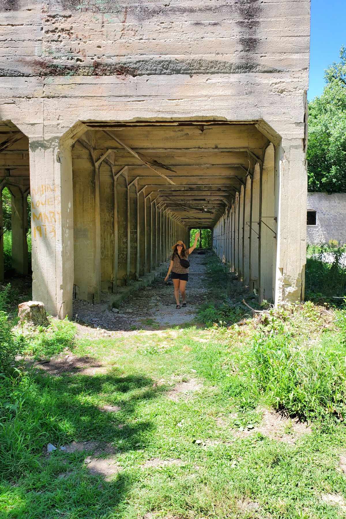 a woman standing inside building structure with endless openings  holding one arm up