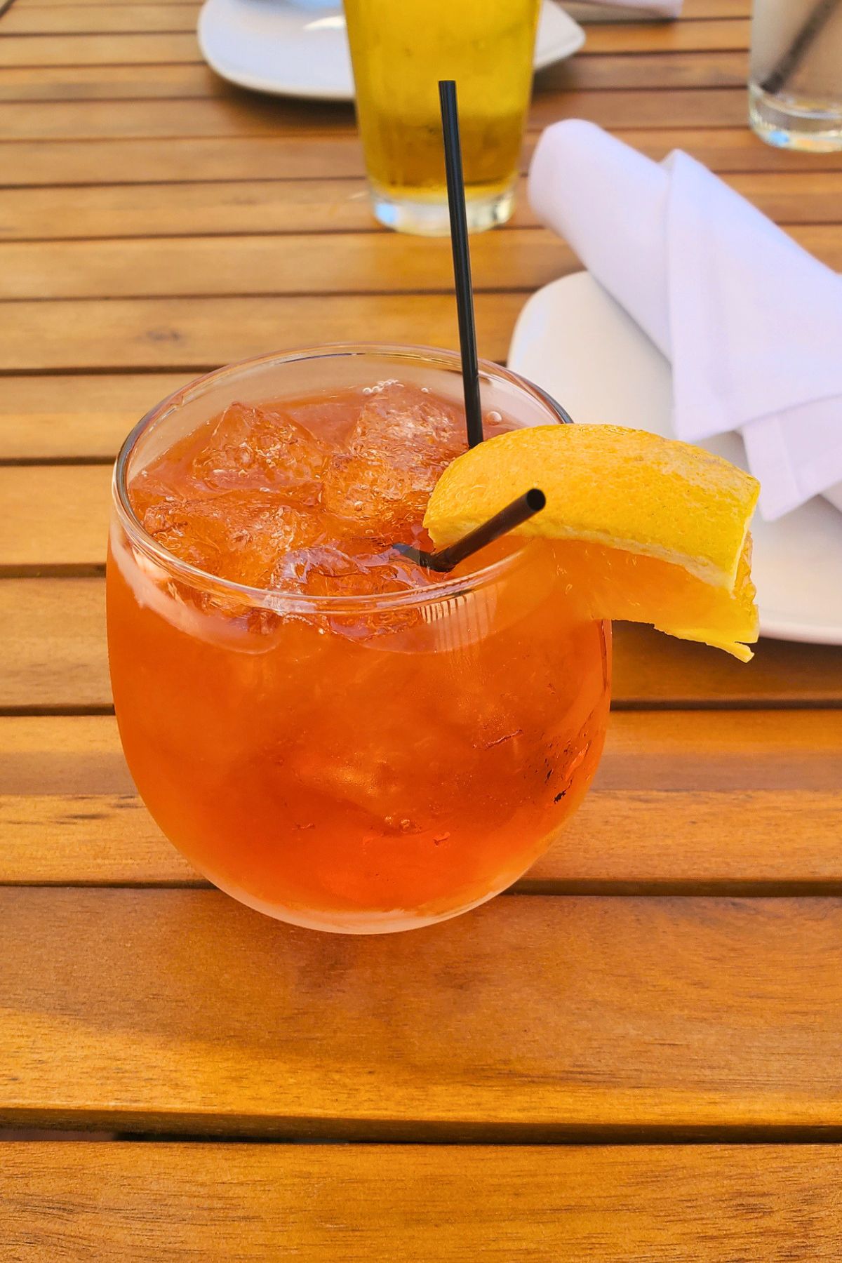Aperol Spritz in a glass with 2 straws and a lemon garnish
