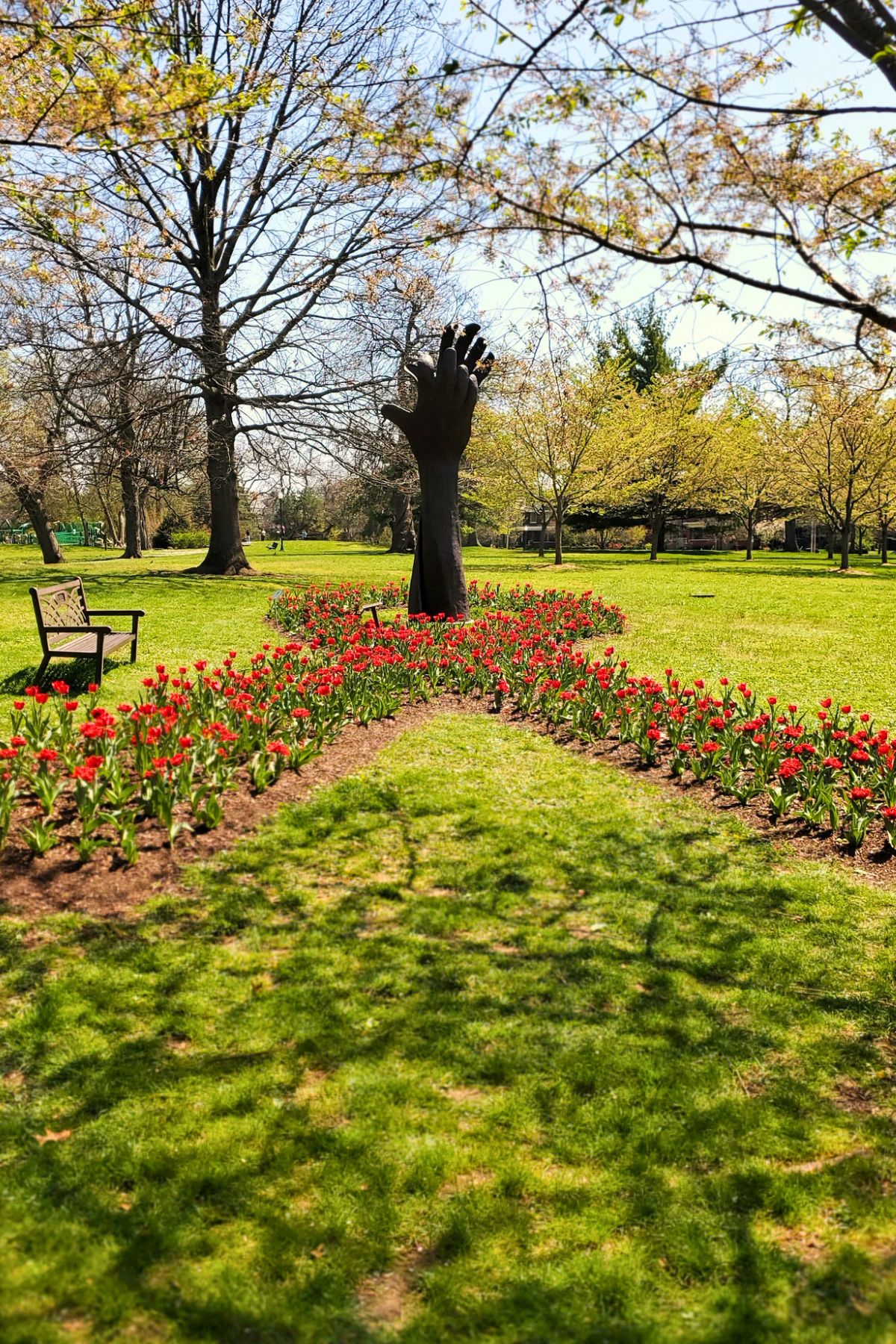 hand sculpture in the middle of red tulips formed in a ribbon symbol