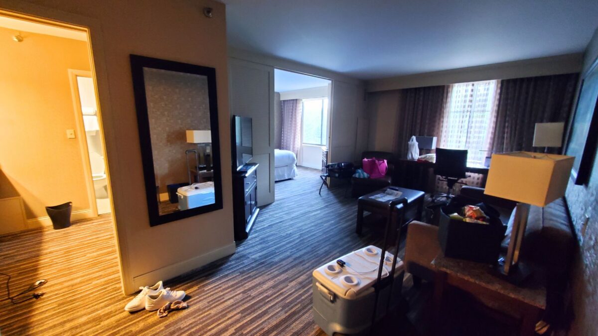 inside the Sheraton Cuyahoga hotel room with living space area with couches, a bedroom with a bed and a bathroom and vanity