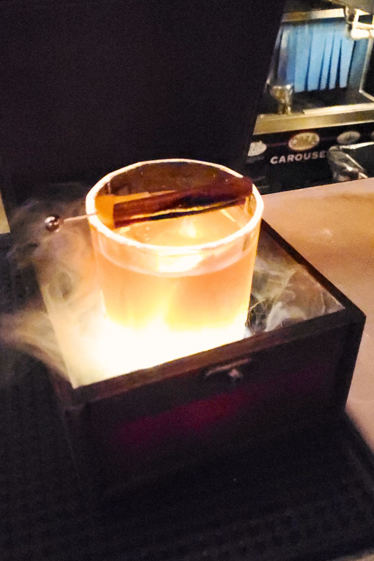 Old fashioned cocktail in a smoke box with smoke coming out of it