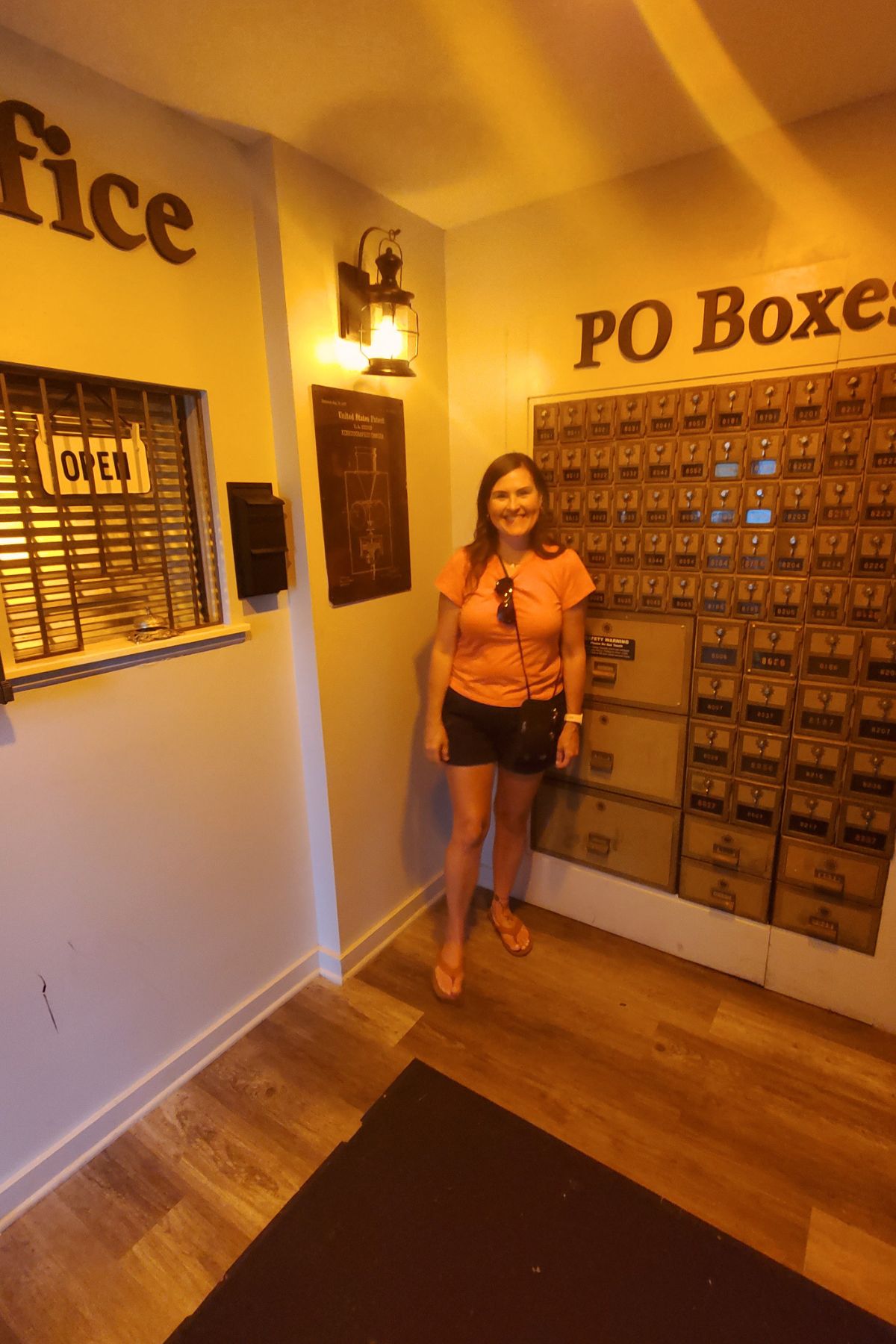 girl standing outside Speakeasy that looks like a post office outside with fake post office boxes and PO Boxes sign