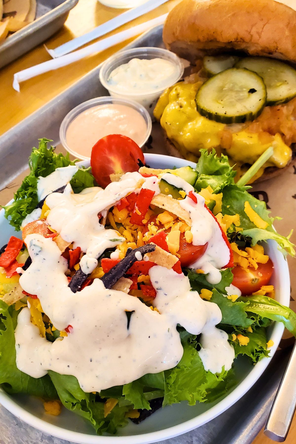 Cheeseburger on a gluten free bun next to a salad with ranch dressing