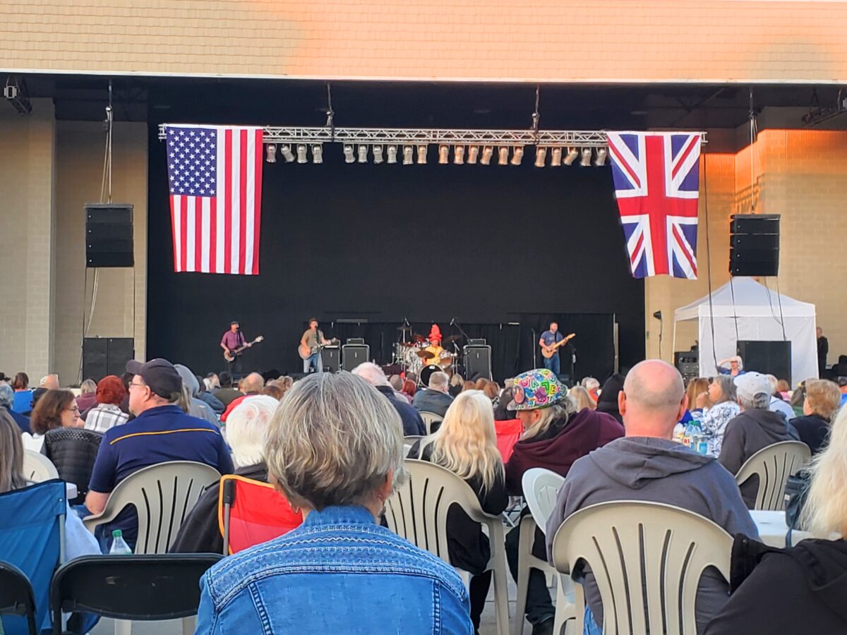 outdoor concert with band on stage and people sitting in audience